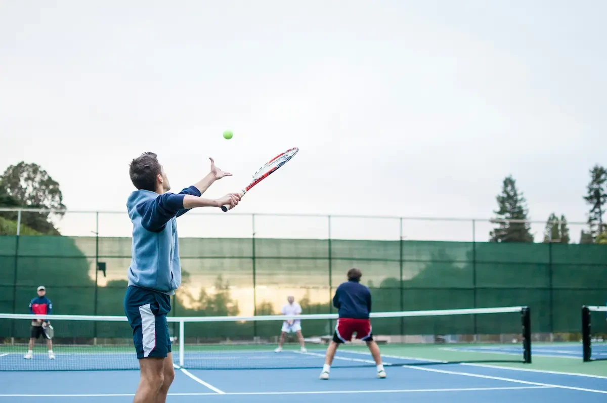 Man doet opslag tijdens tennis dubbelspel